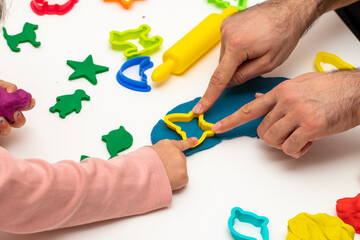 Girl playing dough with her father. father daughter playing game on white background. Making various shapes with dough. Close-up. Father's Day.