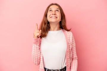 Little caucasian girl isolated on pink background indicates with both fore fingers up showing a...