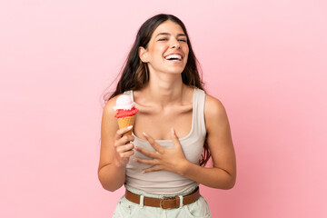 Young caucasian woman with a cornet ice cream isolated on pink background smiling a lot