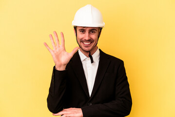Young architect caucasian man isolated on yellow background smiling cheerful showing number five with fingers.