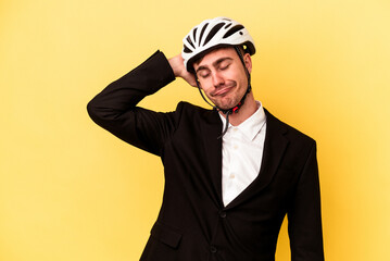 Young caucasian business man wearing a bike helmet isolated on yellow background touching back of head, thinking and making a choice.
