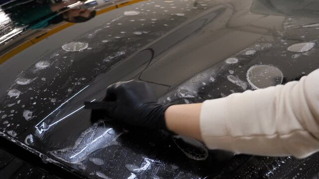 Close up to PPF installation process on a front headlight and hood. PPF is a Paint Protection Film which protect paint from scratches and stone chips. Concept of: Guard, Protect, Car, New, Work.	
