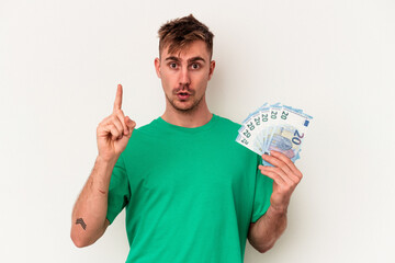 Young caucasian man holding bank notes isolated on white background having some great idea, concept of creativity.