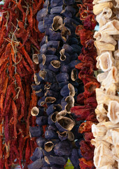 Dried vegetables in the traditional way strung on threads and hung on the street. Dried red hot and sweet peppers, eggplant