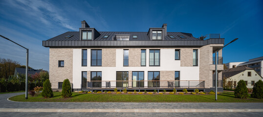 Modern exterior of luxury townhouse. Green lawn and pavement.