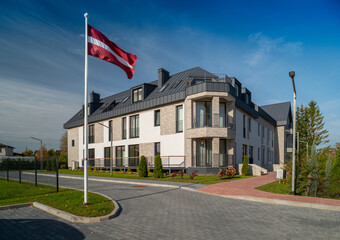 Modern exterior of luxury huge townhouse. Residential complex. Latvian flag.