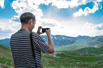 Man tourist takes a photo of beautiful summer mountain landscape. Durmitor National Park. Montenegro.