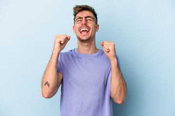 Fototapeta premium Young caucasian man isolated on blue background celebrating a victory, passion and enthusiasm, happy expression.