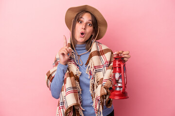 Young caucasian woman holding vintage lantern isolated on pink background having some great idea, concept of creativity.