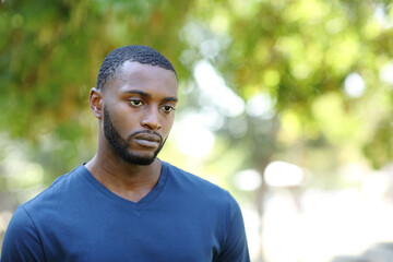 Fototapeta premium Worried man with black skin distracted looking away in a park