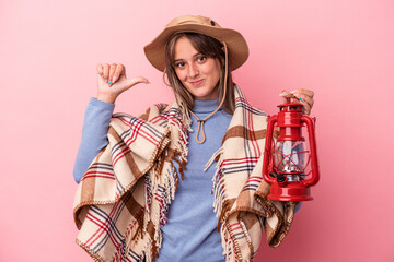 Young caucasian woman holding vintage lantern isolated on pink background feels proud and self confident, example to follow.
