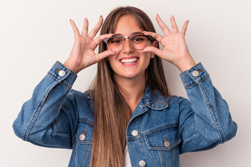 Young caucasian woman isolated on white background showing okay sign over eyes
