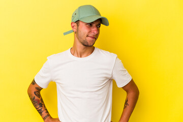 Young caucasian man with tattoos isolated on yellow background  confused, feels doubtful and unsure.