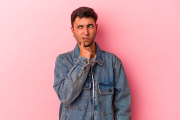 Fototapeta premium Young caucasian man with tattoos isolated on yellow background looking sideways with doubtful and skeptical expression.