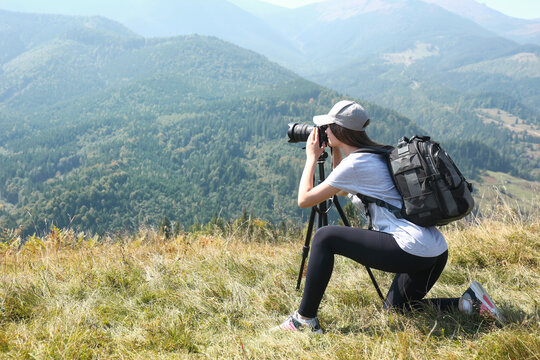 Woman taking photo of mountain landscape with modern camera on tripod outdoors