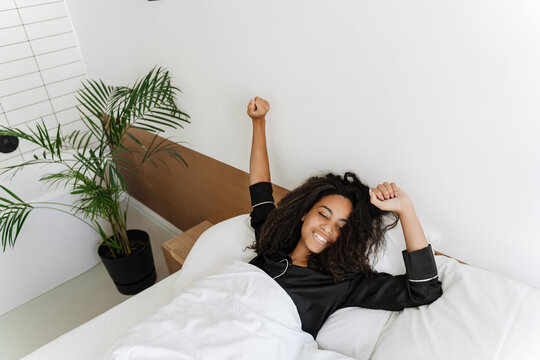 Young Black Woman Stretching Her Body While Lying In Bed After Sleep