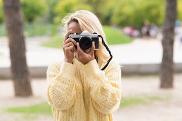 Woman taking a photo with a camera in a park