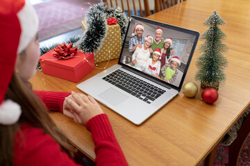 Naklejka na ściany i meble Caucasian woman in santa hat making laptop christmas video call with smiling multi generation family