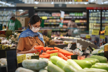 Asian woman wearing protect face mask and  shopping fruit, vegetable in grocery department store.