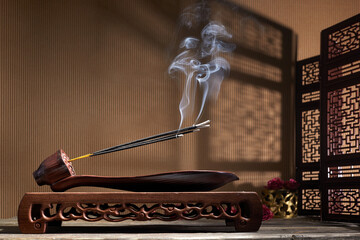 Smoke from burning incense sticks standing on lotus incense holder