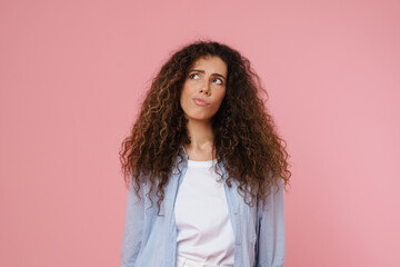 Young brunette woman with wavy hair frowning and looking aside