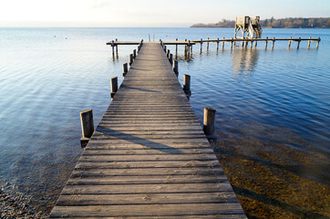 Fototapeta premium a long wooden pier in Herrsching on Lake Ammersee in Bavaria on a clear December day (Germany) 