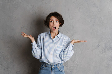 Young brunette woman expressing surprise while holding copyspace