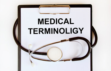On the tablet for writing the text MEDICAL TERMINOLIGY, around it is wrapped a stethoscope. - obrazy, fototapety, plakaty