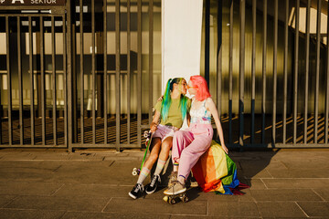Fototapeta na wymiar Young lesbian couple kissing while sitting with rainbow flag