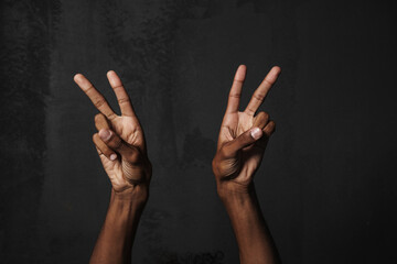Black man's hands showing peace gesture at camera