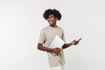 Young black man using cellphone while posing with laptop