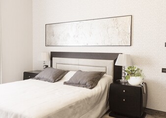 Simple modern bed with pillows and soft blanket, lamp, furniture on wooden floor.