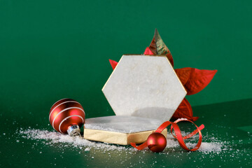 Marble hexagon podium with winter Christmas holiday decor. Red baubles, ribbon, poinsettia flower....