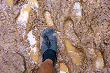 View from above on pair of trekking shoes in a mud, Hiking boots stuck in mud.