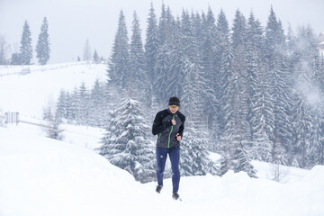 Fototapeta na wymiar Young man running in mountains in winter cold weather