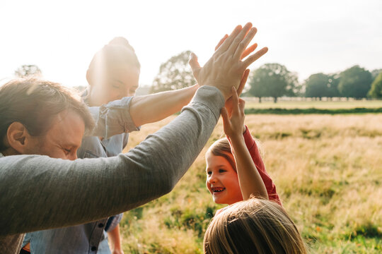 Happy family doing high-five in park on weekend