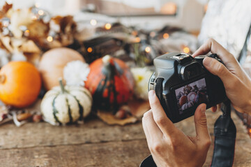 Photographer holding camera and taking photo of halloween pumpkins against a rustic autumn...