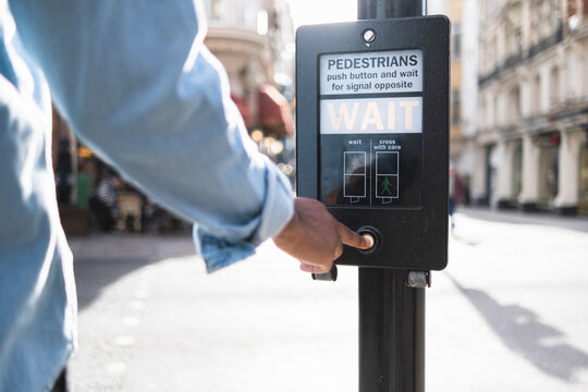 Man pushing button on traffic signal in city