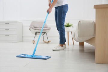 Woman cleaning parquet floor with mop at home, closeup