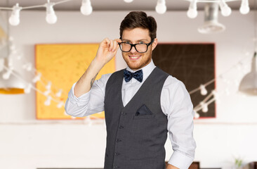 fashion, style and vintage concept - happy man in festive suit and eyeglasses over restaurant...