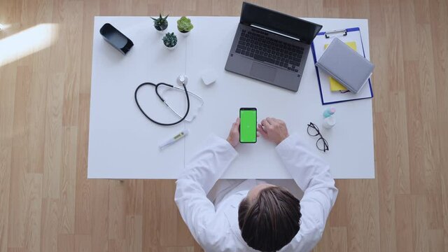 Doctor scrolling and swiping healthcare app on smartphone with green screen