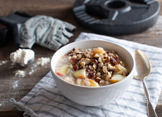 Fitness breakfast bowl with porridge, whey protein, sauteed apples and roasted hazelnuts