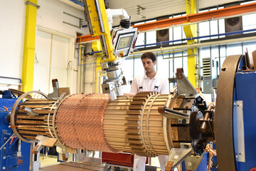 young mechanical engineering workers operate a machine for winding copper wire - manufacture of...