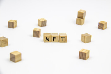 Word NFT (non fungible token) written on the wood cubes on white background. Non-fungible tokens concept NFT.