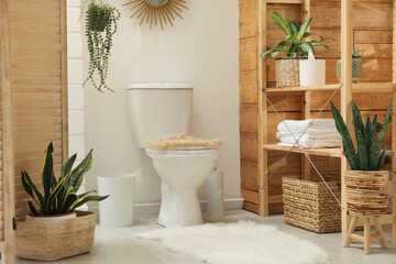 Toilet bowl and green houseplants in bathroom. Interior design