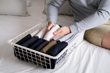 Closeup of hands of an man tidy up things in mesh storage containers. Vertical storage of clothing....