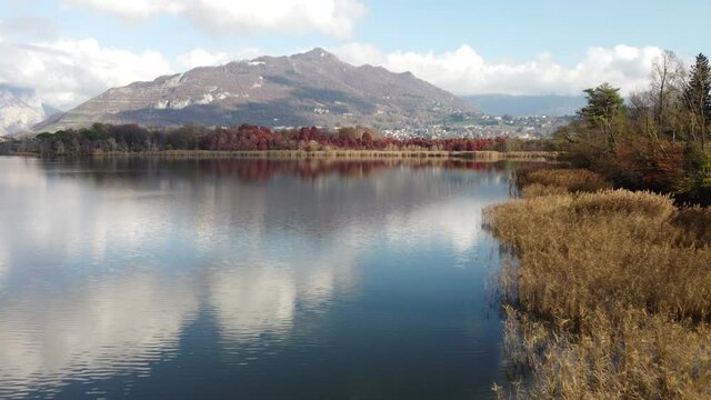 Aerial view of an alpine lake and the surrounding mountains and vegetations reflected on a cloudy day, Brianza, Lombardy, Italy