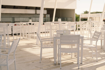 Fototapeta na wymiar White table and chairs in cafe outdoors. Street cozy restaurant