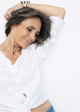 Smiling Woman With Hand Raised Against White Background