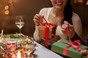 winter holidays and celebration concept - close up of happy smiling people opening christmas gifts...